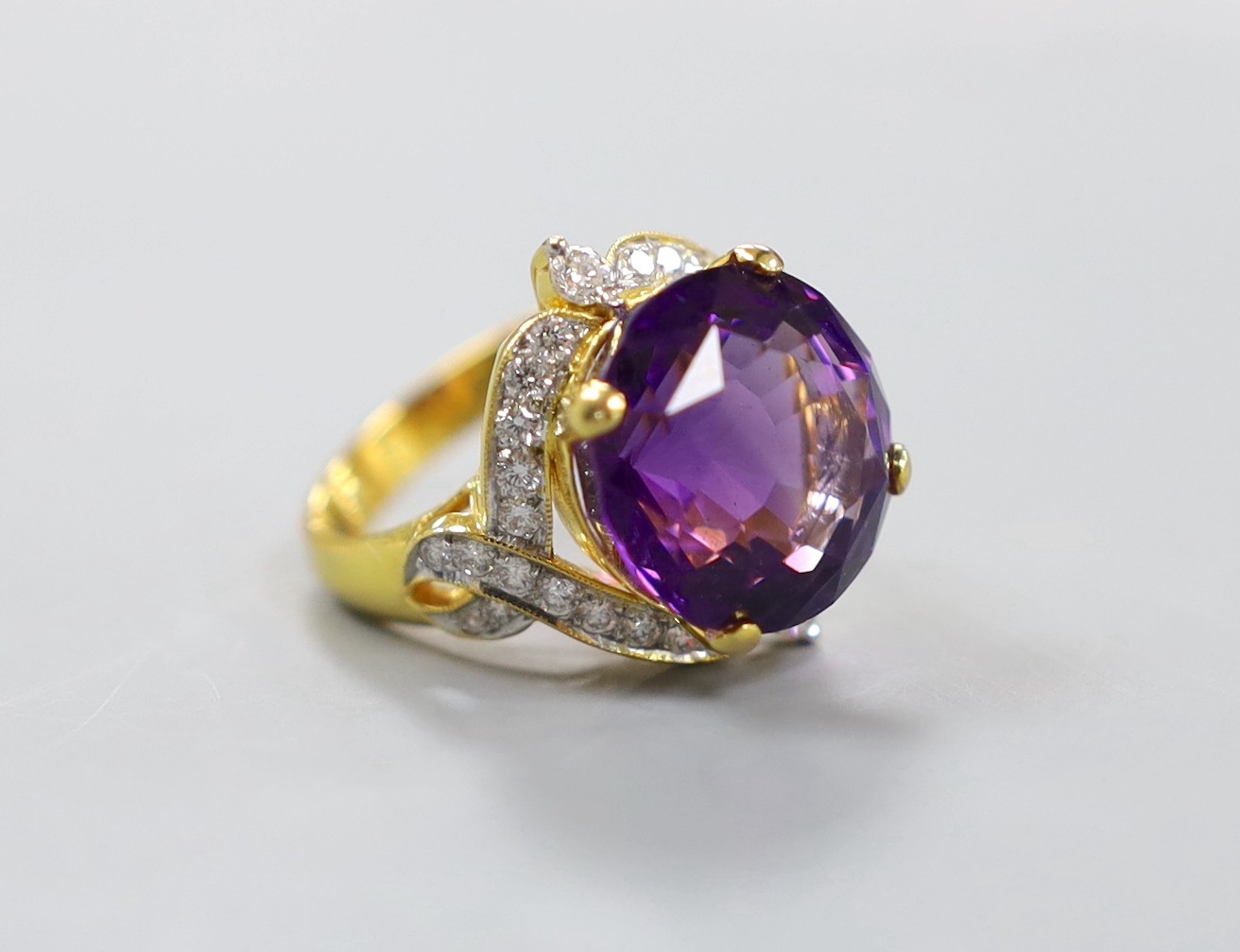 A modern yellow metal, round cut amethyst and diamond chip set cluster dress ring, size M, gross weight 10.9 grams.